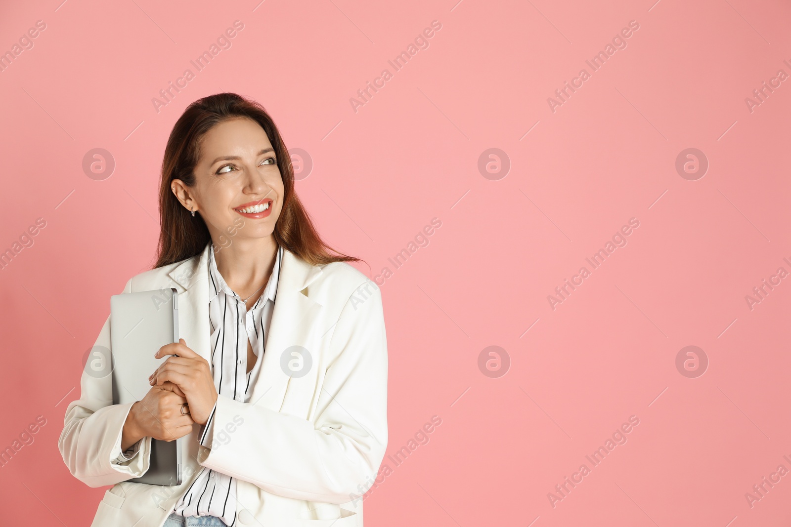 Photo of Beautiful woman in stylish white jacket with laptop on pink background, space for text