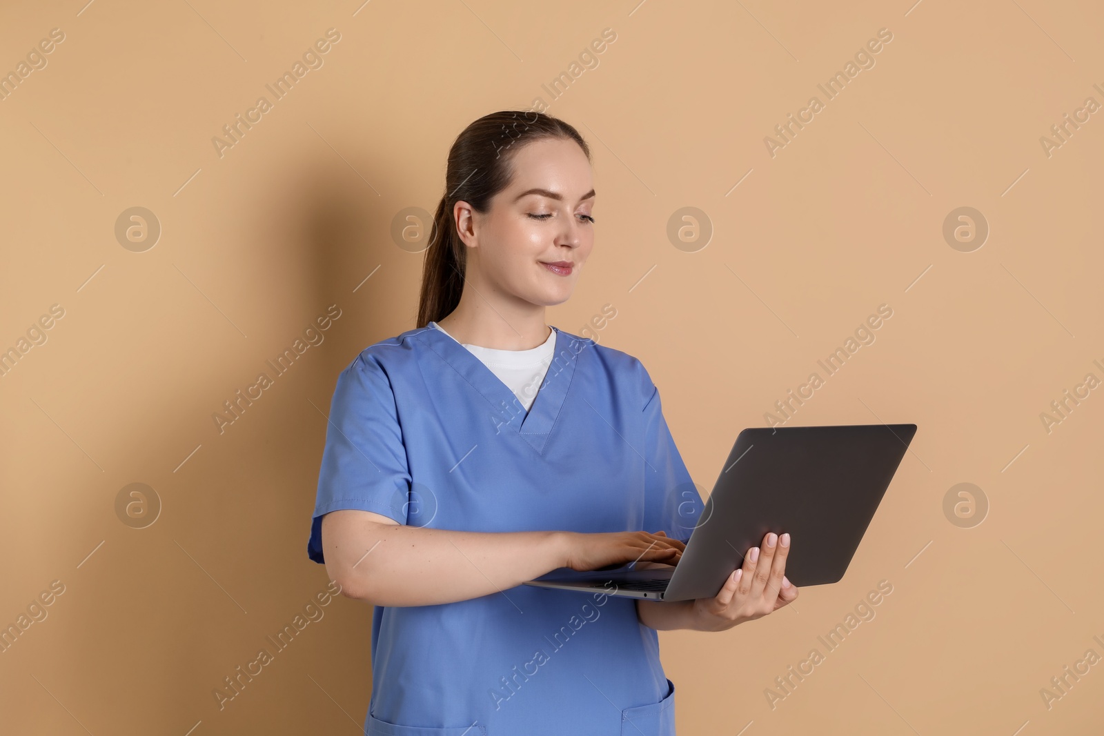 Photo of Professional nurse working with laptop on dark beige background