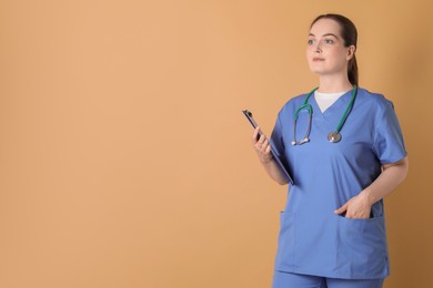 Photo of Portrait of professional nurse with stethoscope and clipboard on dark beige background