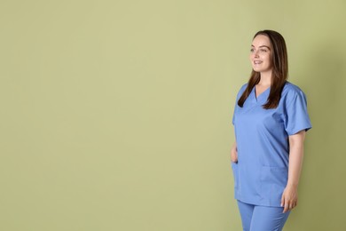 Photo of Professional nurse in uniform on pale green background. Space for text