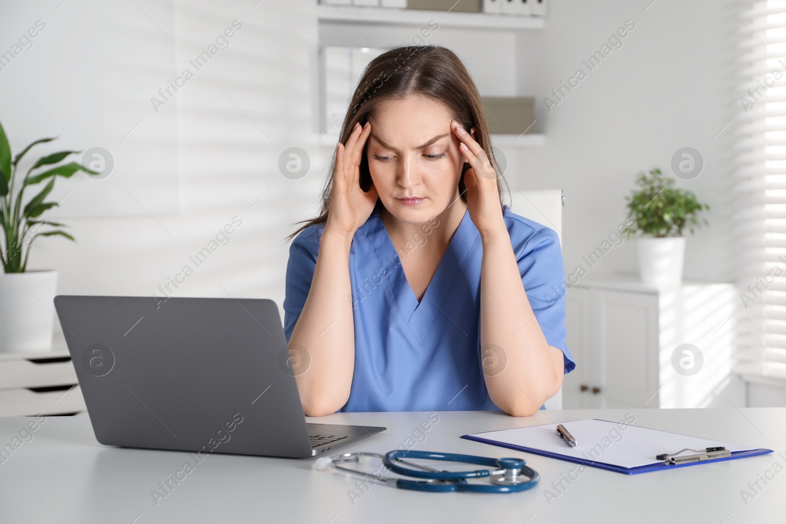 Photo of Tired nurse working at desk in hospital