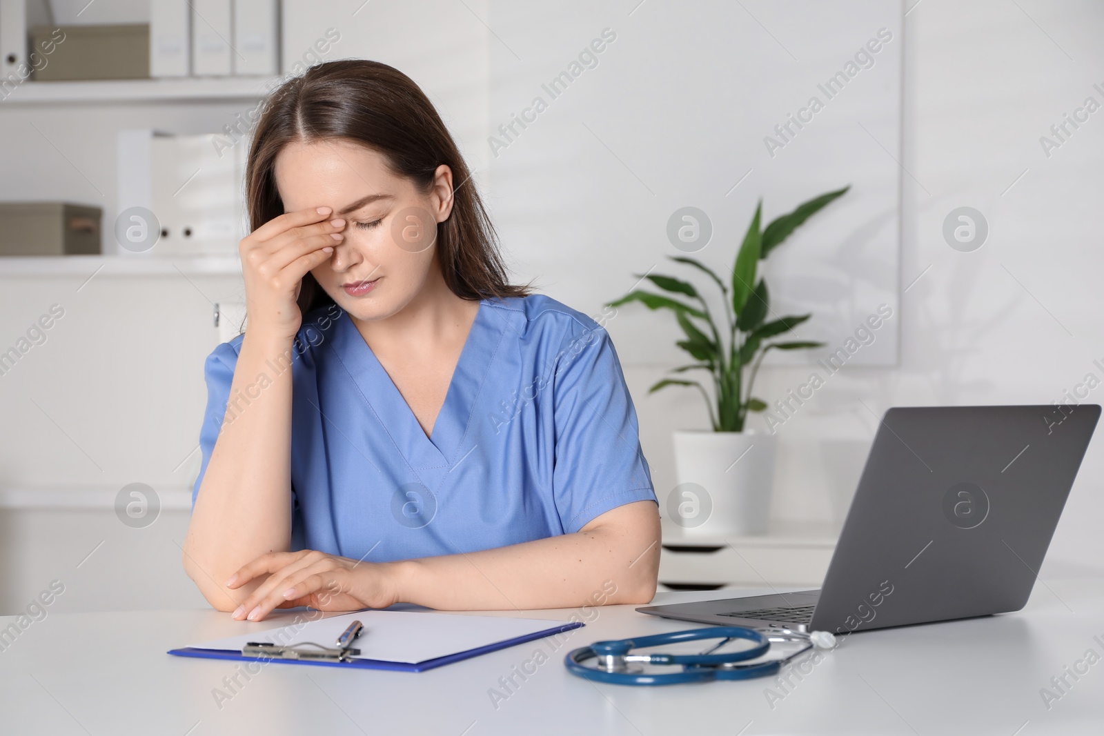 Photo of Tired young nurse at workplace in hospital