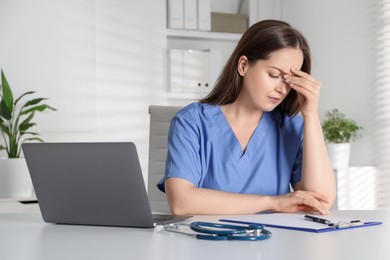 Photo of Tired young nurse at workplace in hospital