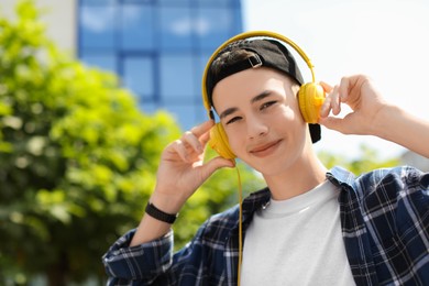 Portrait of teenage boy with headphones outdoors. Space for text