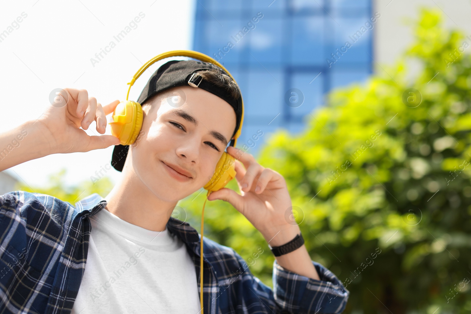 Photo of Portrait of teenage boy with headphones outdoors. Space for text