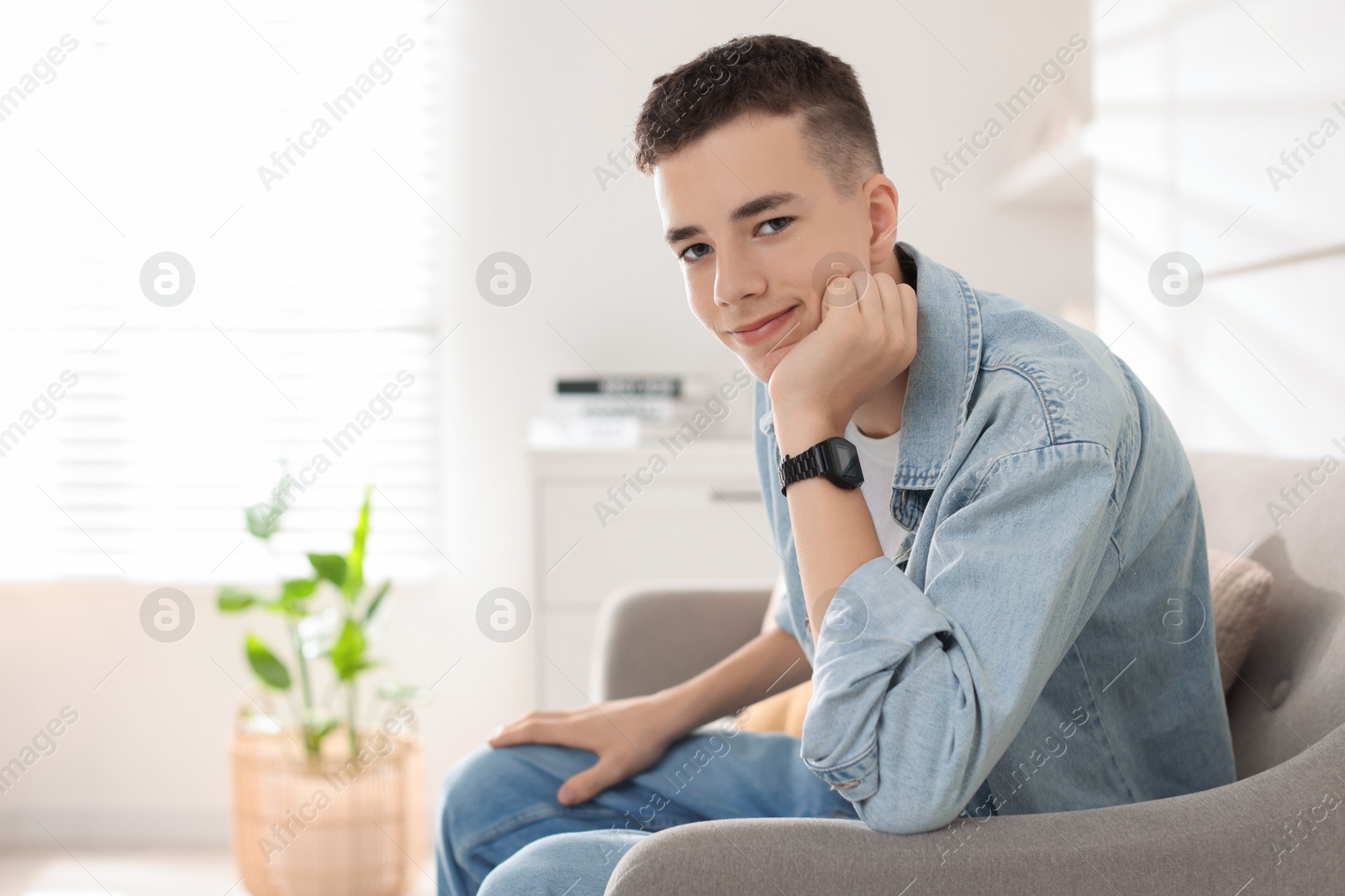 Photo of Portrait of teenage boy on sofa at home. Space for text