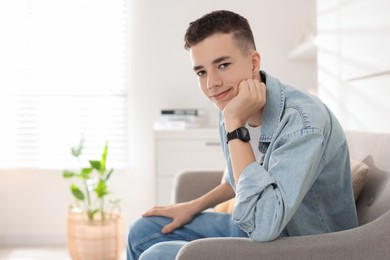 Photo of Portrait of teenage boy on sofa at home. Space for text