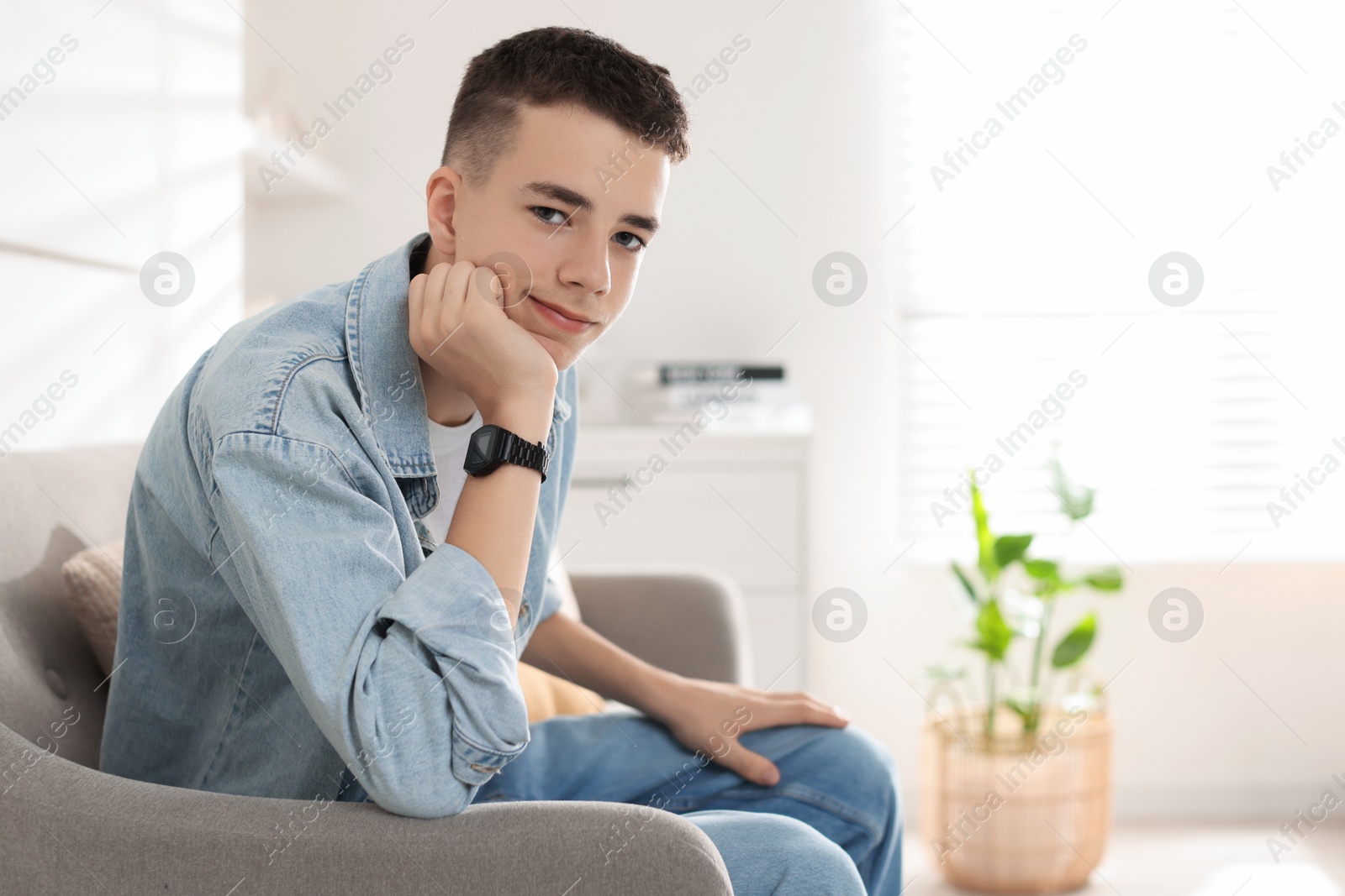 Photo of Portrait of teenage boy on sofa at home. Space for text