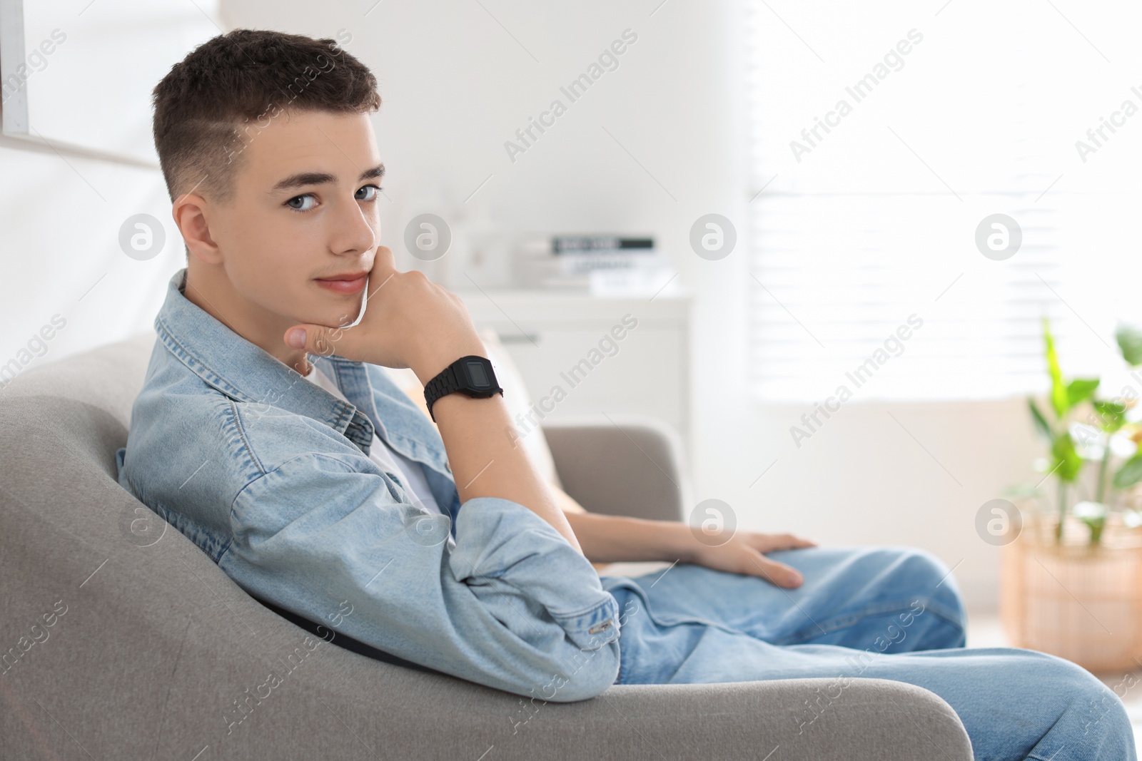 Photo of Portrait of teenage boy on sofa at home. Space for text