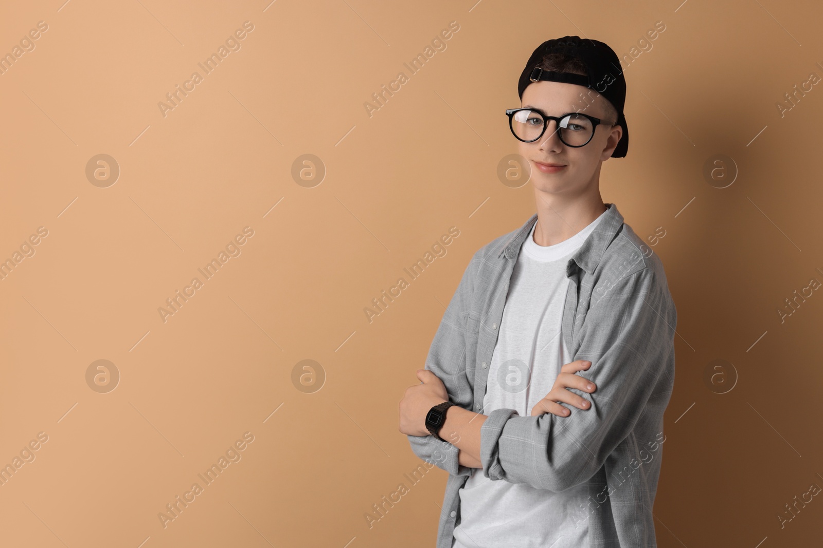 Photo of Portrait of teenage boy with crossed arms on dark beige background. Space for text