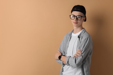 Portrait of teenage boy with crossed arms on dark beige background. Space for text