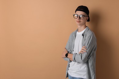 Photo of Portrait of teenage boy with crossed arms on dark beige background. Space for text