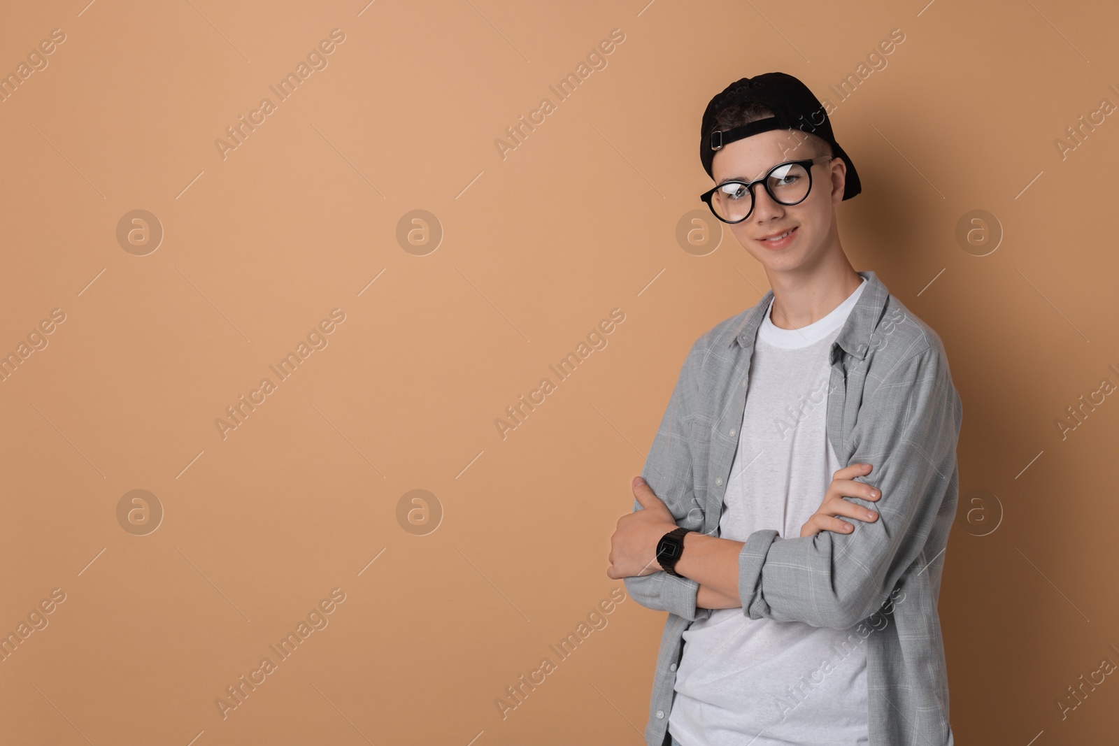 Photo of Portrait of teenage boy with crossed arms on dark beige background. Space for text