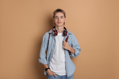 Photo of Portrait of teenage boy with backpack on dark beige background