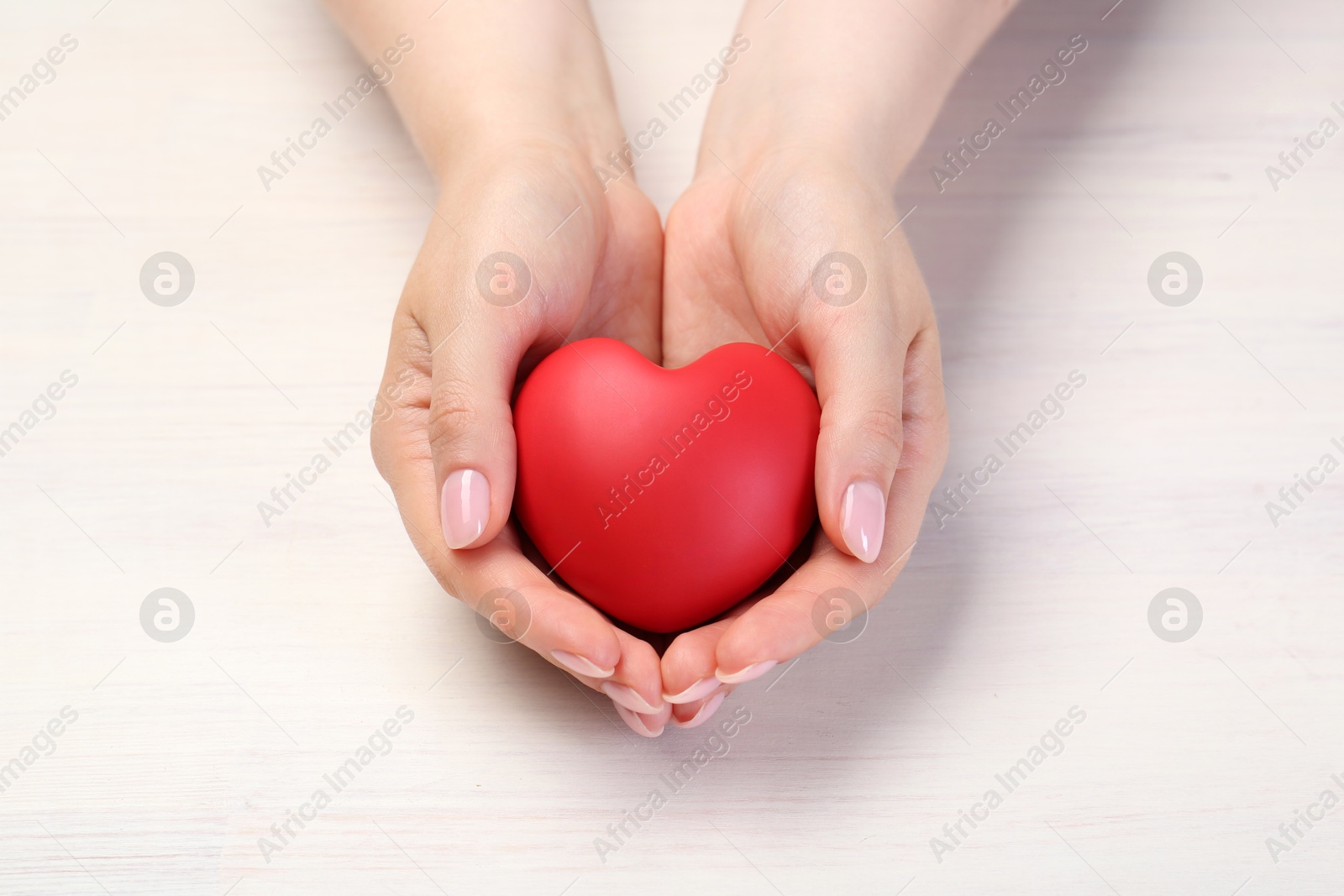 Photo of Woman with red decorative heart at white wooden table