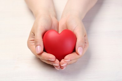 Photo of Woman with red decorative heart at white wooden table, closeup