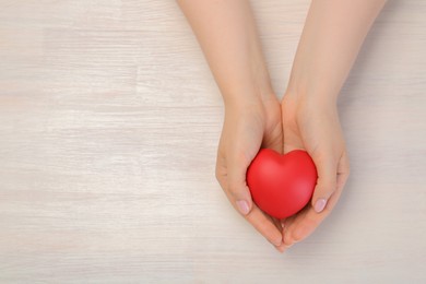 Photo of Woman with red decorative heart at white wooden table, top view. Space for text