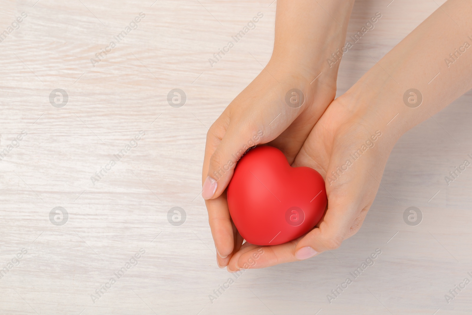 Photo of Woman with red decorative heart at white wooden table, top view. Space for text