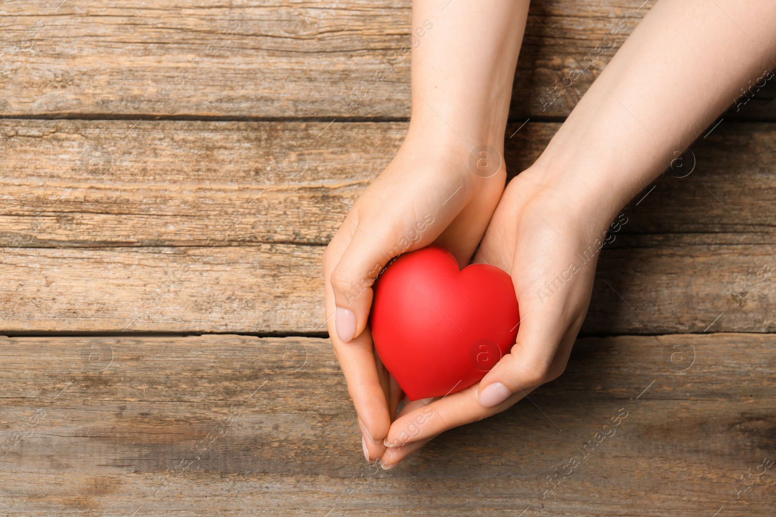 Photo of Woman with red decorative heart at wooden table, top view. Space for text