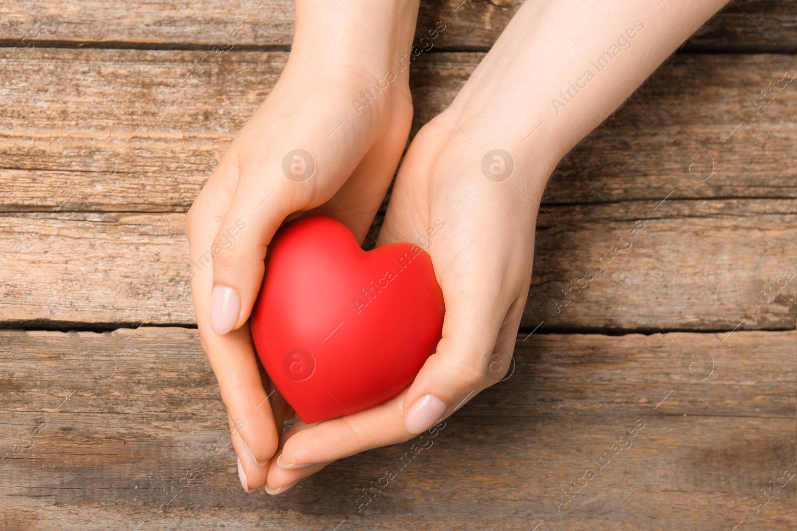 Photo of Woman with red decorative heart at wooden table, top view