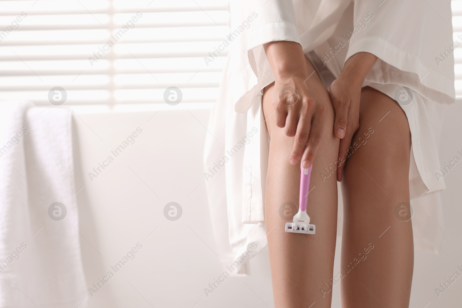 Photo of Woman shaving leg on bathtub indoors, closeup. Space for text