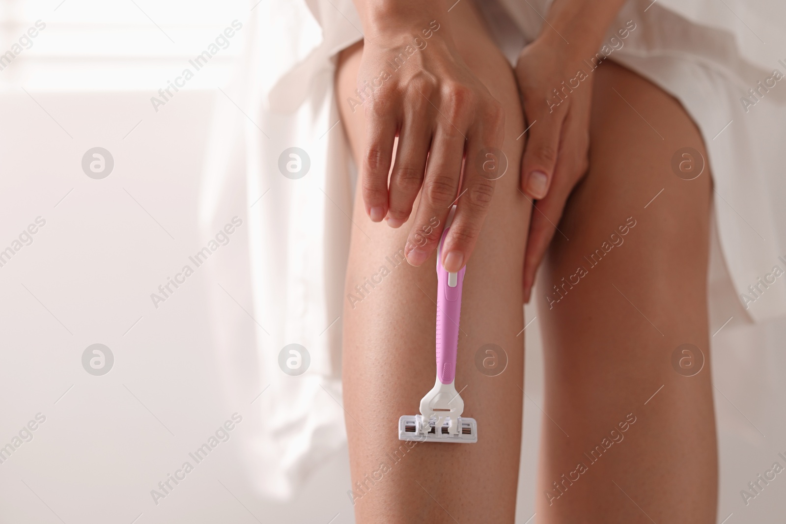 Photo of Woman shaving leg at home, closeup. Space for text