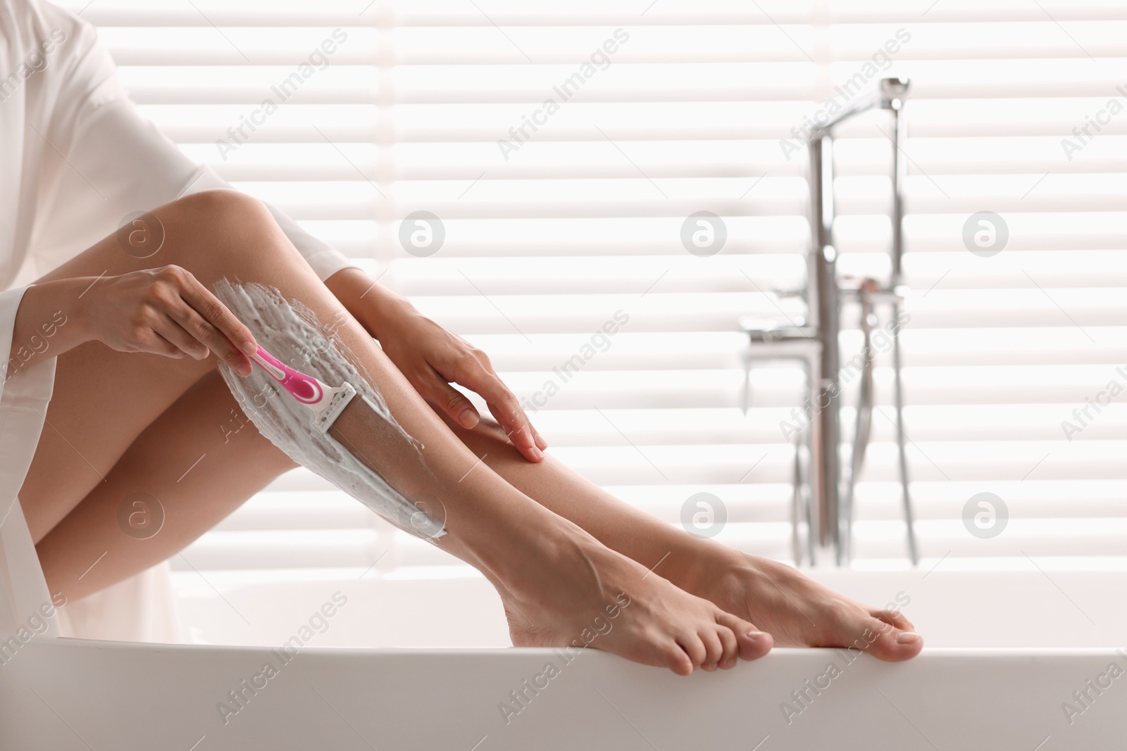 Photo of Woman shaving leg in bathtub indoors, closeup. Space for text