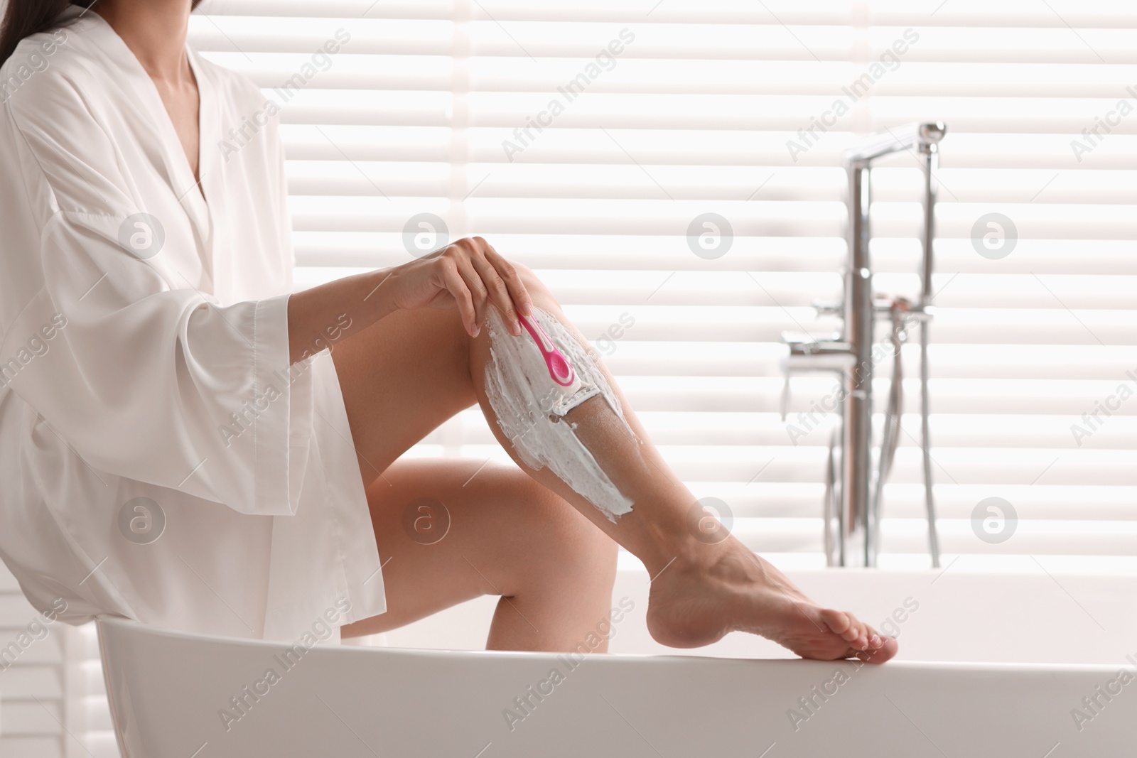 Photo of Woman shaving leg in bathtub indoors, closeup. Space for text