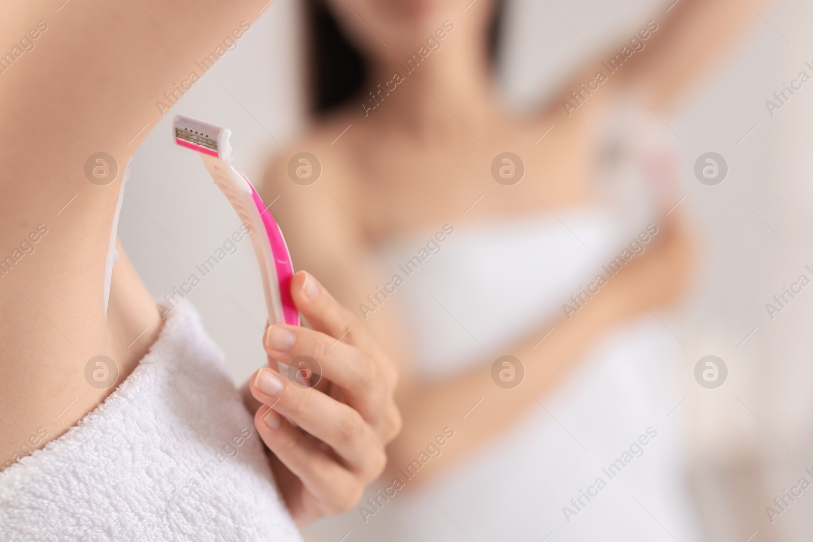 Photo of Woman shaving armpit near mirror indoors, closeup. Space for text