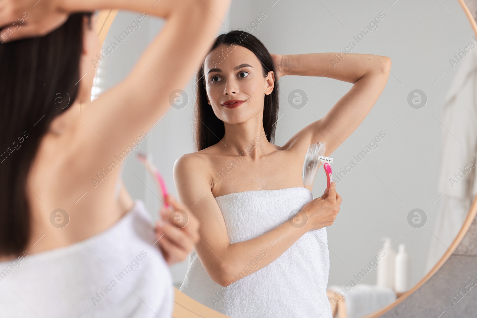 Photo of Woman shaving armpit near mirror indoors, selective focus