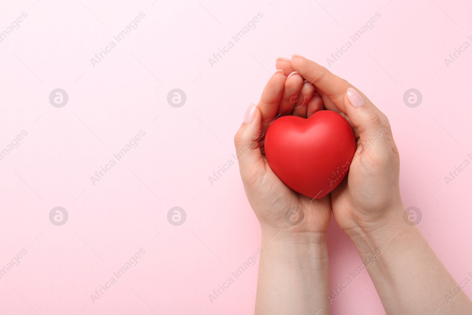 Photo of Woman holding red heart on pink background, top view. Space for text