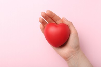 Photo of Woman holding red heart on pink background, top view. Space for text