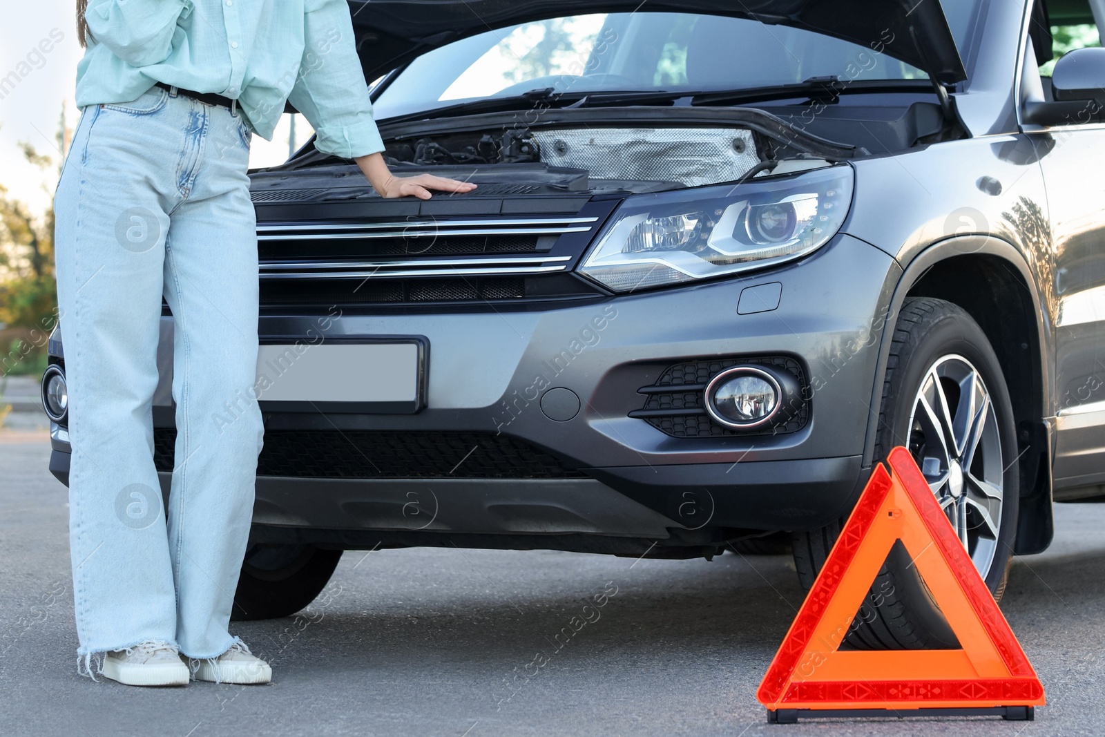 Photo of Stressed woman talking on phone near broken car outdoors