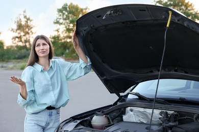 Photo of Stressed woman standing near broken car outdoors