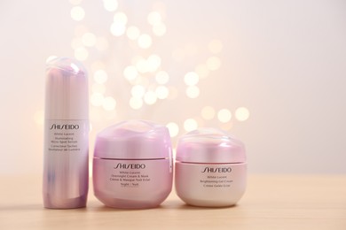 Photo of Leiden, Netherlands - June 11, 2024: Shiseido care cosmetic products on wooden table against light background with blurred lights, space for text