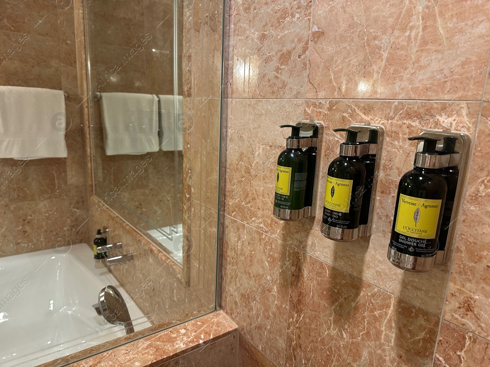 Photo of Berlin, Germany - July 2, 2024: Bottles with body care products on tiled wall in Regent Berlin Hotel bathroom