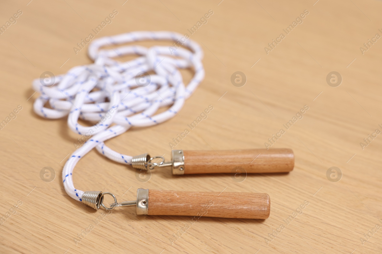 Photo of Skipping rope on wooden table, closeup. Sports equipment