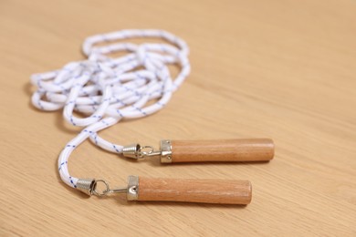 Skipping rope on wooden table, closeup. Sports equipment