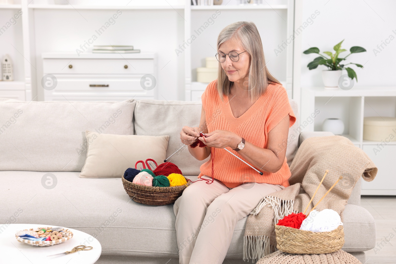 Photo of Beautiful senior woman knitting on sofa at home