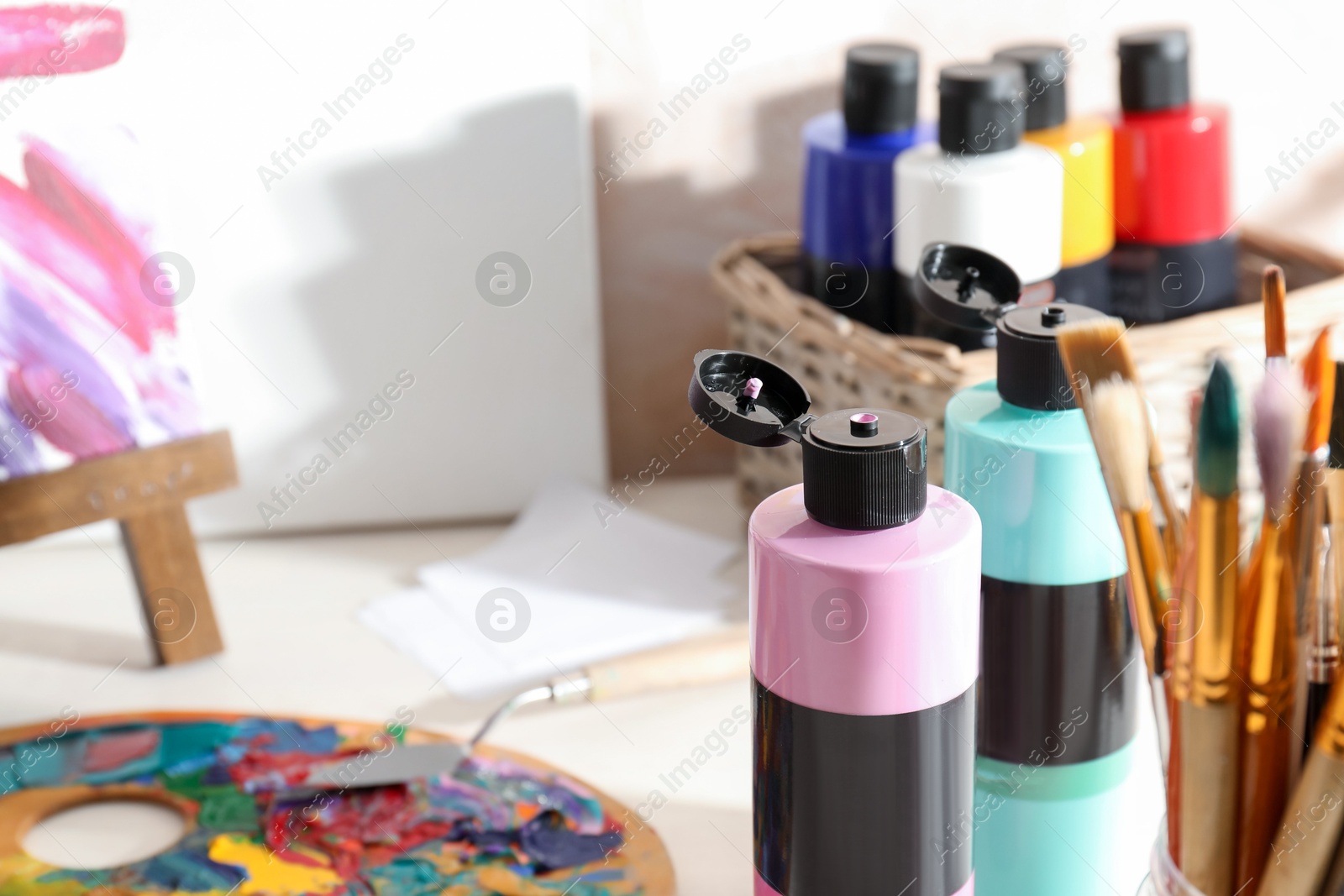 Photo of Acrylic paints of different colors, brushes and palette on table indoors