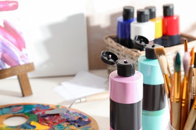 Photo of Acrylic paints of different colors, brushes and palette on table indoors