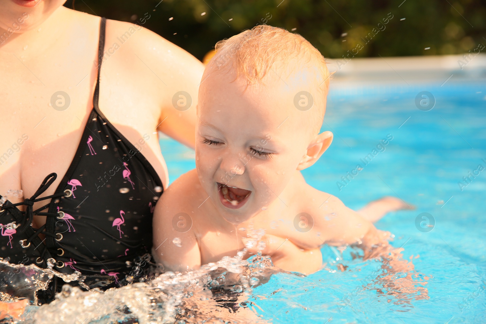 Photo of Mother and her son having fun in swimming pool outdoors