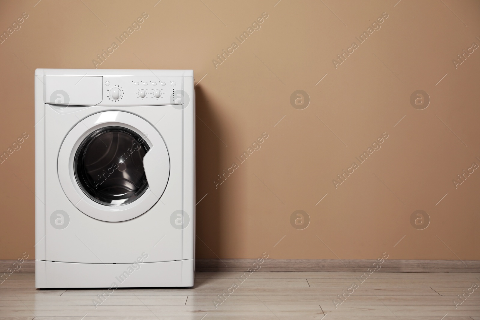 Photo of Washing machine near beige wall indoors, space for text