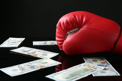 Photo of Red boxing glove and dollar banknotes on black mirror surface