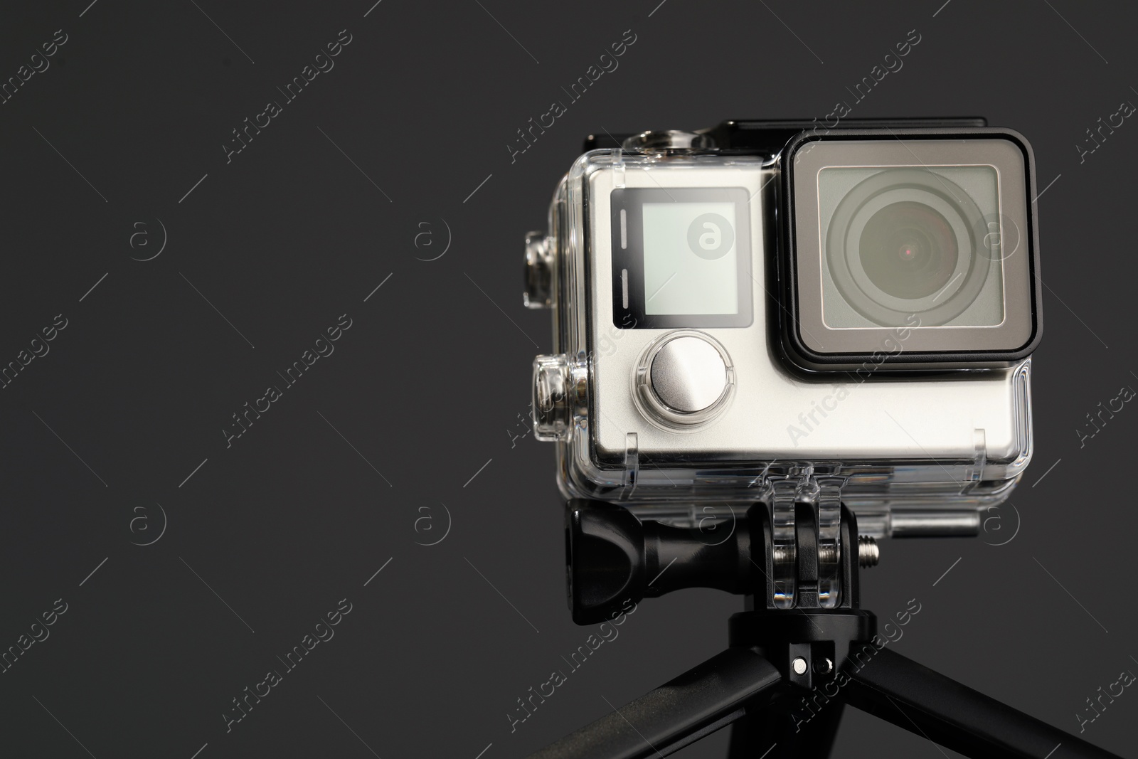 Photo of Modern action camera and tripod on grey background, closeup. Space for text