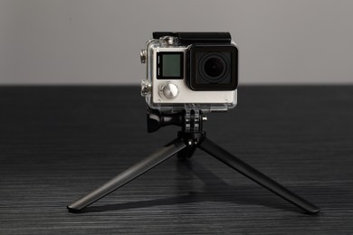 Modern action camera and tripod on grey wooden table