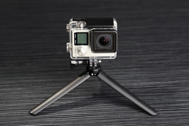 Modern action camera and tripod on grey wooden table