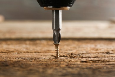 Screwing screw into wooden surface, closeup view