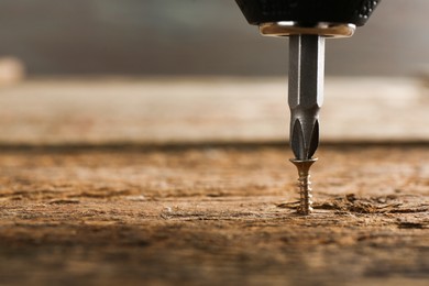 Photo of Screwing screw into wooden surface, closeup. Space for text