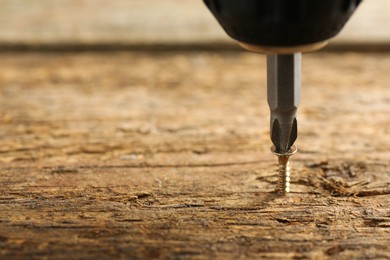 Photo of Screwing screw into wooden surface, closeup. Space for text